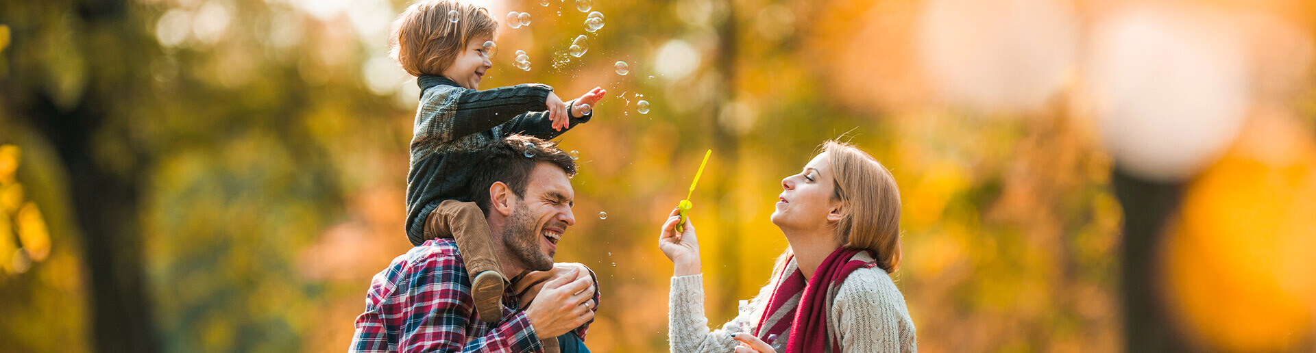 young family blowing bubbles outside