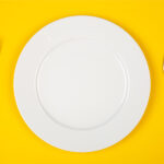 Aerial view of a white plate on a yellow background
