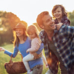 Mom and dad take their two children for an outdoor picnic at a park in Columbus, OH