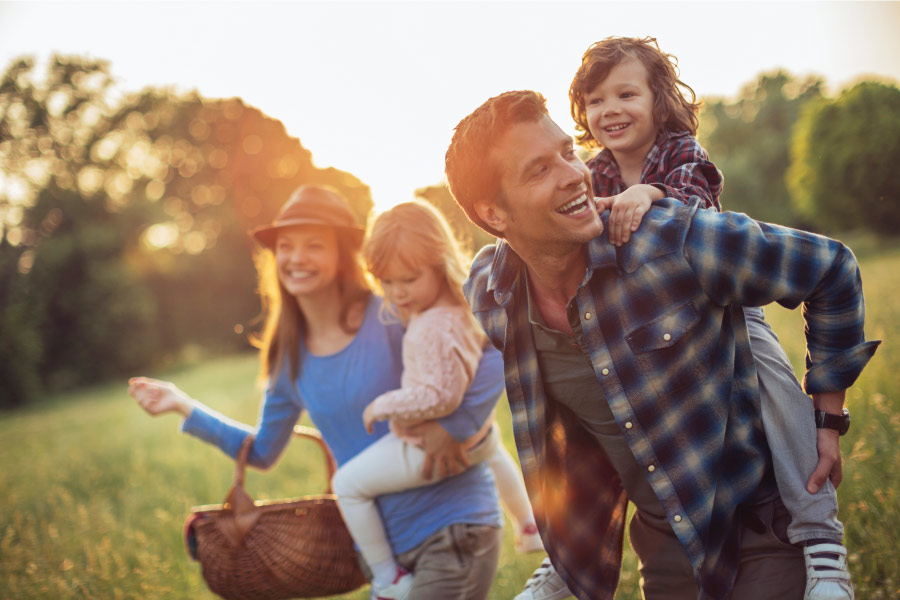 Mom and dad take their two children for an outdoor picnic at a park in Columbus, OH